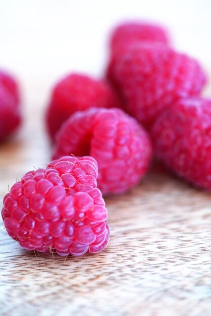 Close up view on bright raspberries on wooden background