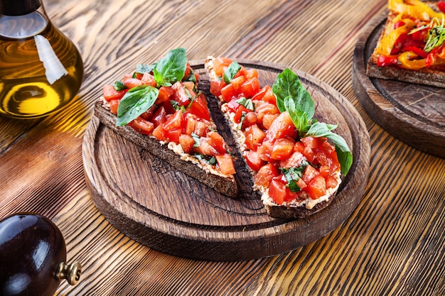 Close up view on bruschetta with tomato on wooden board. Fresh italian bruschetta on wooden table with copy space for text or design. Picture for menu or recipe. Fresh vegan snack