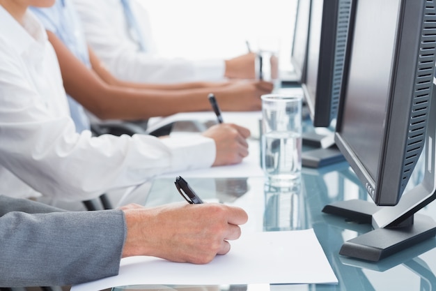 Close up view of business people writing on paper 