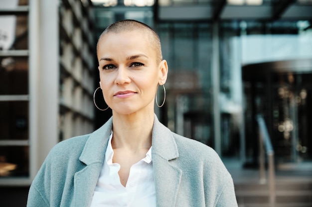 Close-up view of a business woman looking at the camera while standing outside office building. Business concept.