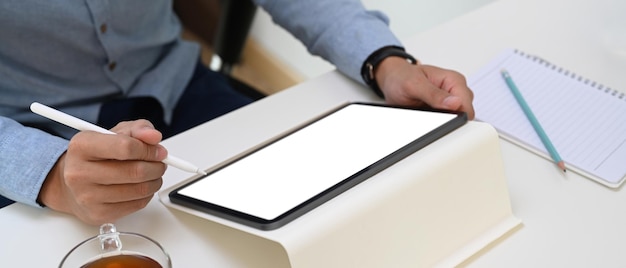 Close up view businessman holding mock up digital tablet with empty screen and stylus pen .