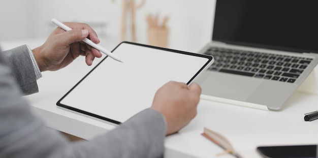 Close-up view of businessman writing his plan on blank screen tablet in his modern office