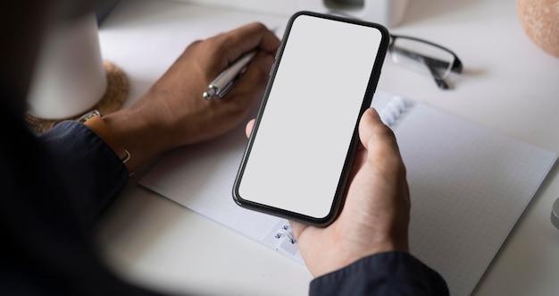 Close up view businesswoman holding smart phone and writing on notebook