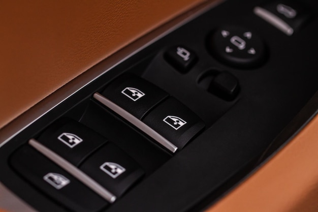 Close up view of button controlling window in modern car\
interior vehicle interior detail door handle with windows\
controls