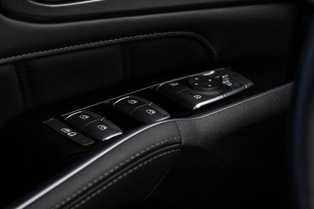 Close up view of button controlling window in modern car\
interior. vehicle interior detail. door handle with windows\
controls