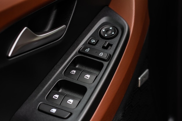 Крупным планом вид кнопки управления окном в интерьере современного автомобиля. Деталь интерьера автомобиля. Дверная ручка с элементами управления стеклоподъемником