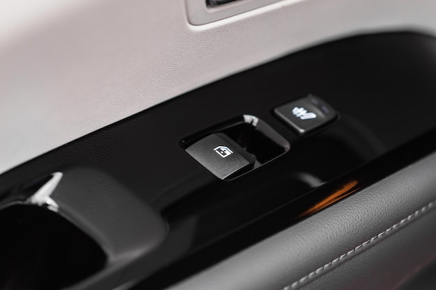 Close up view of button controlling window in modern car\
interior. vehicle interior detail. door handle with windows\
controls