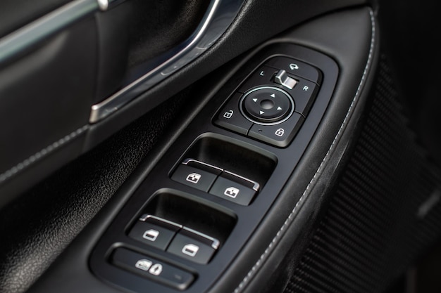 Close up view of button controlling window in modern car\
interior. vehicle interior detail. door handle with windows\
controls