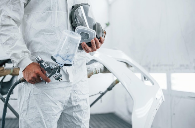 Close up view Caucasian automobile repairman in uniform works in garage