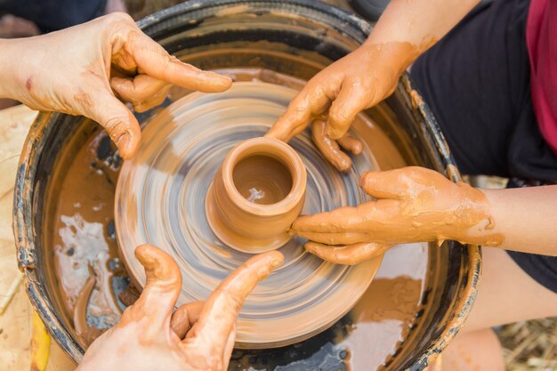 A close up view on ceramic production process on potters wheel with children