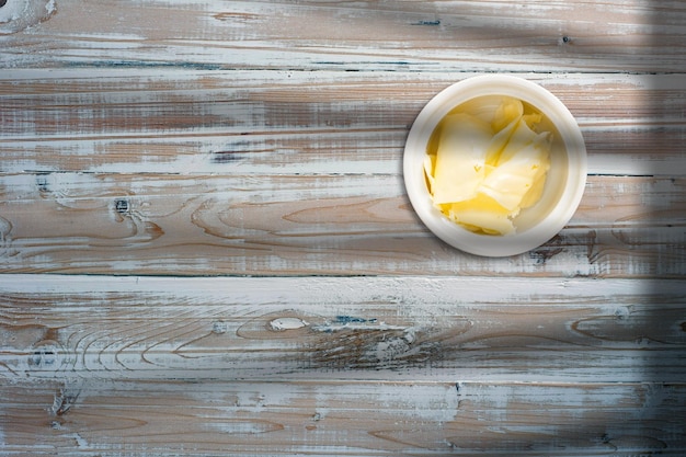 Photo close up view of cheese slices on ceramic bowl over wooden table