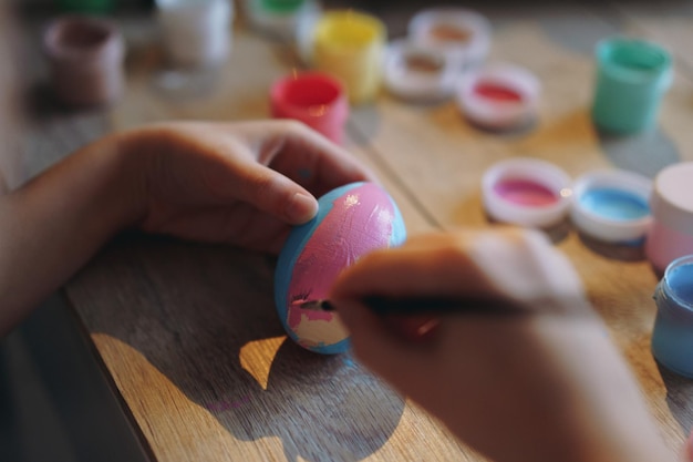 Close up view of child hands colouring easer agg with gouache paint