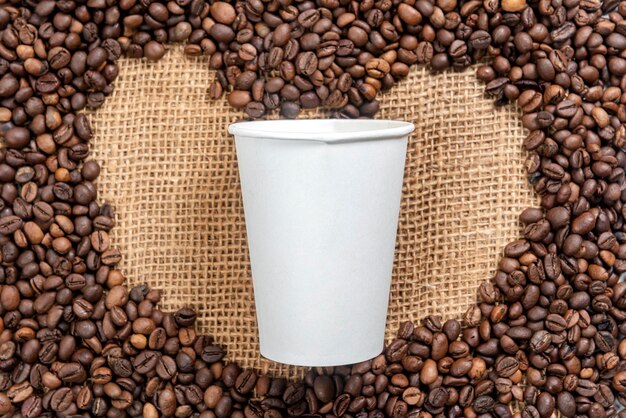 Close up view of coffee beans with heart shape and white plastic cup