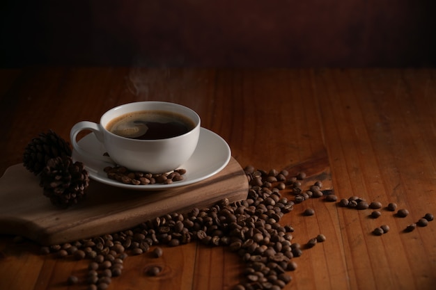 Close up view of a cup of hot coffee on wooden tray decorated with coffee beans on wooden table