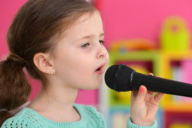 Close up view of cute little girl singing with microphone