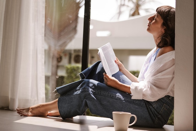 Close up view of cute woman reading a book at home