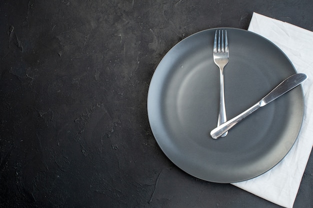 Close up view of cutlery set on a black plate on white towel on dark color background with free space