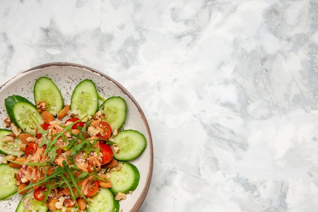 Close up view of delicious salad decorated with chopped cucumber and greens on stained white surface with free space