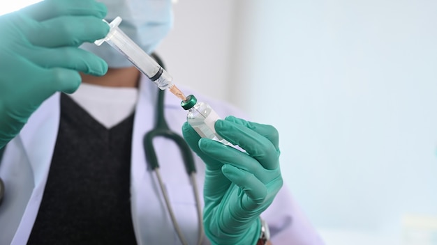 Close up view of doctor in hospital holding a syringe with liquid vaccines.