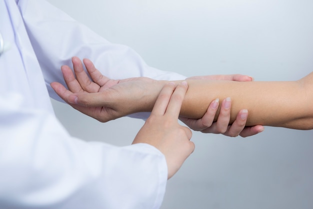 A close-up view of the doctor's hand holding a heart rate monitor on the patient's wrist