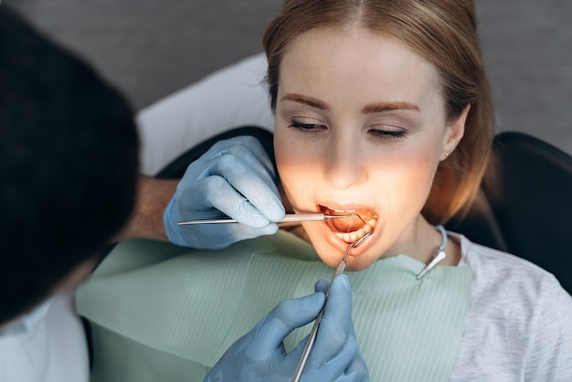 Close-up view, a doctor treats a person's teeth. The dentist examines the patient's teeth with the help of working tools