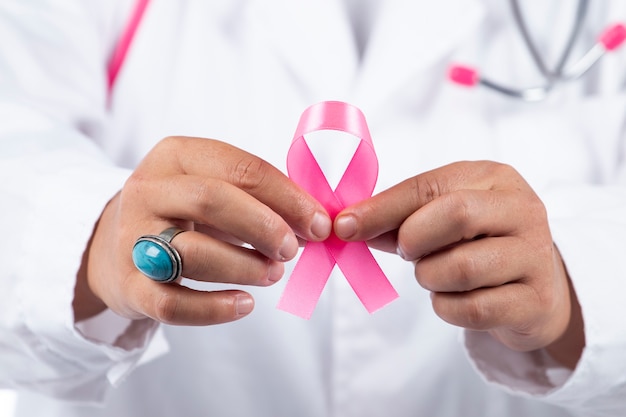 핑크 유 방 암 리본을 들고 여성 의사 손보기를 닫습니다.