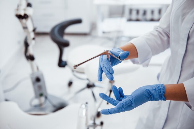 Close up view of female doctor hands that holds retractor instrument.