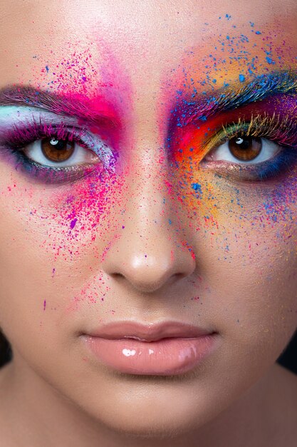 Close up view of female face with bright multicolored fashion makeup. Holi indian color festival inspired.