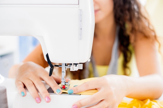 Close up view of female hands working on sewing machine