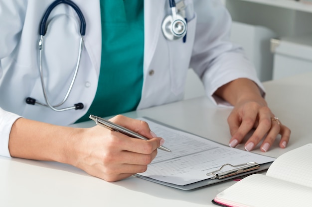 Close up view of female medicine doctors hands filling patient medical form