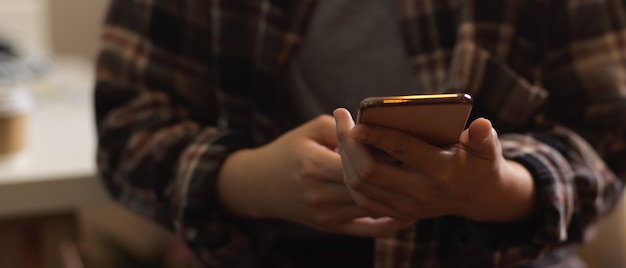 Close up view of female in Scott shirt hand texting on smartphone