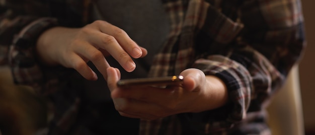 Close up view of female in Scott shirt hand using smartphone