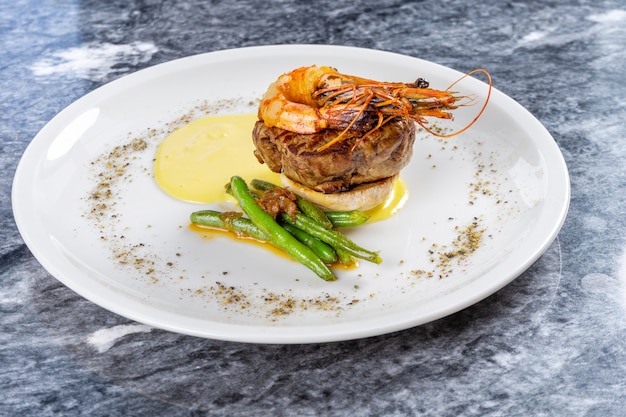 Close up view on Filet Mignon with tiger shrimp, asparagus and mashed potato on white plate