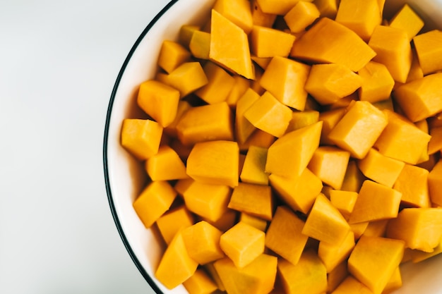 Close up view of fresh, vivid orange pumpkin pieces in a white plate.
