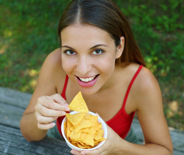 Крупным планом вид сверху красивой молодой женщины есть чипсы тортильи открытый.