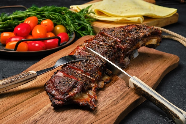 Close up view of grilled lamb breast and flap on wooden cutting board