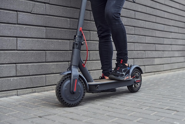 Close up view of guy in casual clothes that riding electric schooter outdoors at sunny daytime