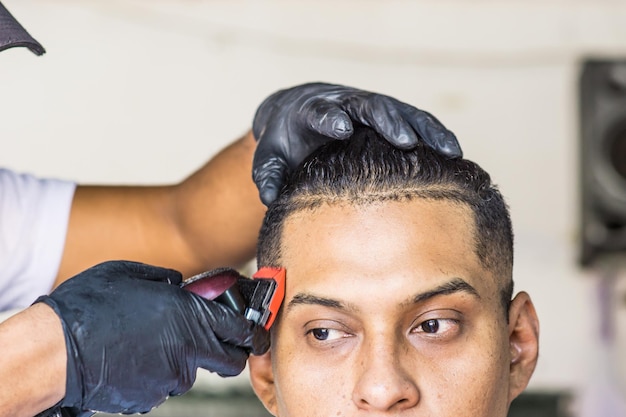 Крупным планом вид руки парикмахера, стригущего волосы костюме бритвой