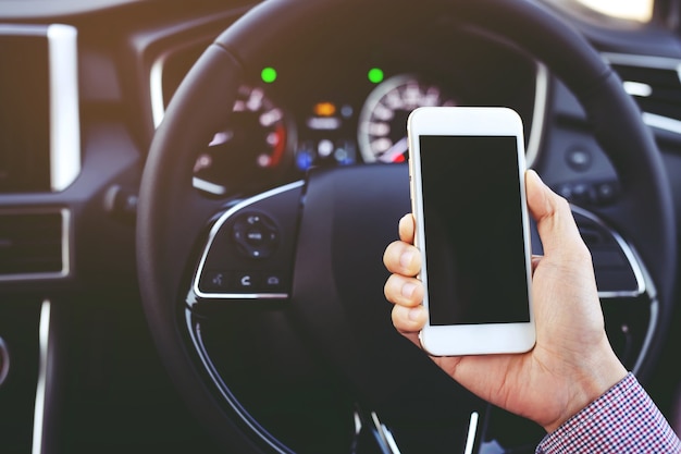 Close up view hand satisfied young businessman looking at mobile smart phone while driver a car.