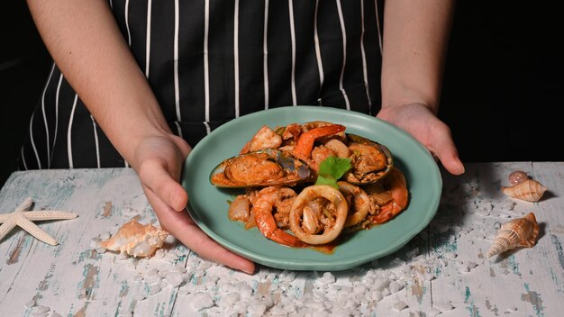 Foto vista ravvicinata delle mani che tengono un piatto di cibo tailandese, curry saltato in padella di pesce in polvere