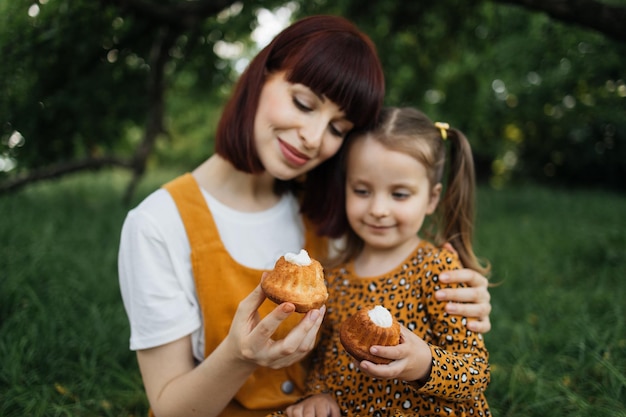 Close up view of happy caucasian mother and her cheerful daughter eating cakes