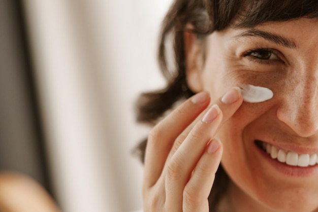 Close up view of happy woman products for skin cream