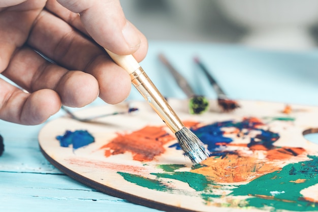 Photo close-up view of highly gifted painter while he is painting his picture.