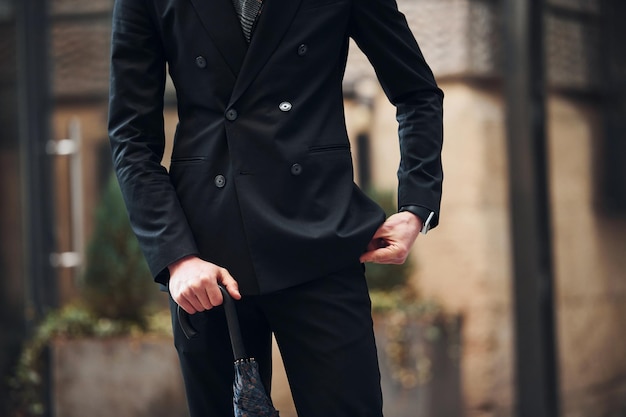 Close up view Holding umbrella Elegant young man in formal classy clothes outdoors in the city