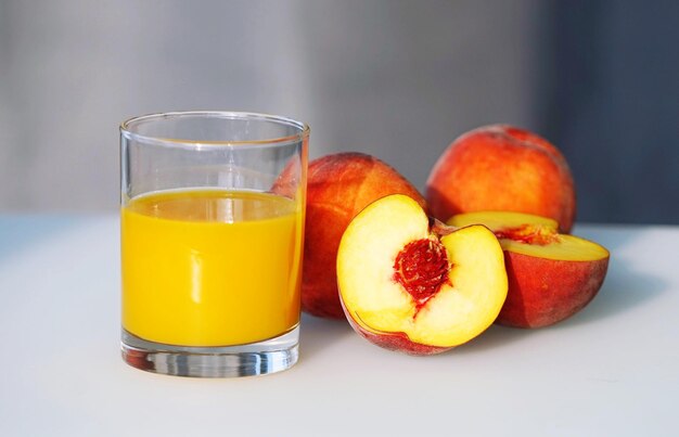 Close up view on juice in glass and group of peaches