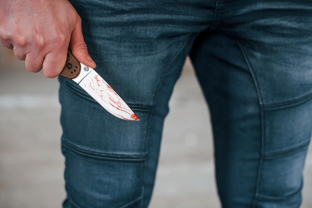 Close up view of killer that standing with knive with blood in hand