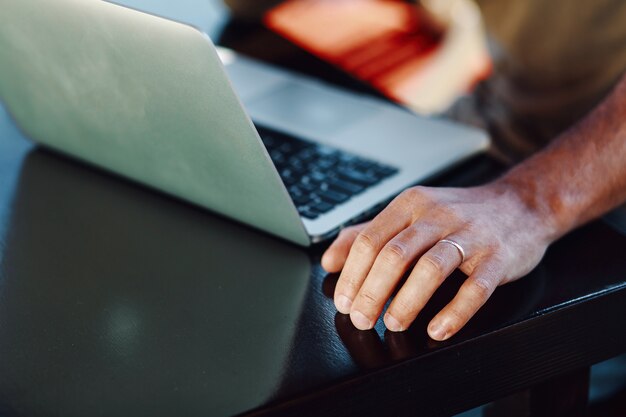 Photo close-up view of laptop and male hand with the ring