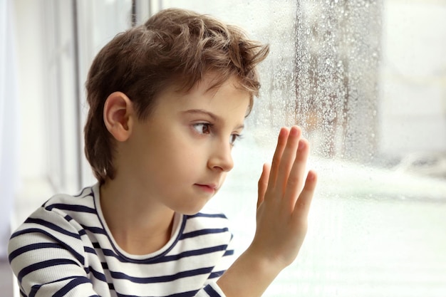 Close up view of little boy looking out of window