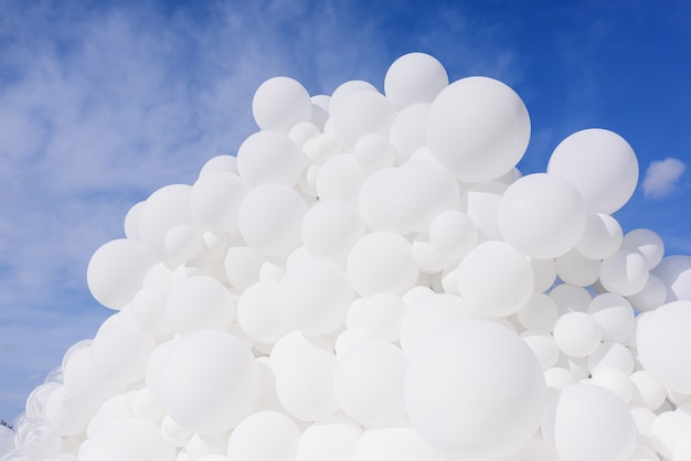 Close up view of a lot of white balloons on the sky background
