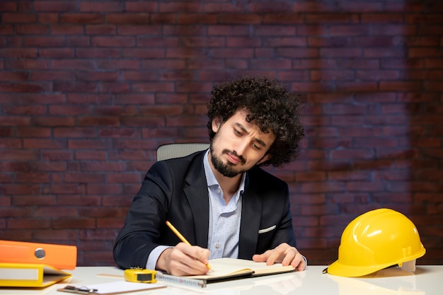 close-up view male engineer sitting behind working place in suit taking notes agenda contractor business builders indoors corporate job work